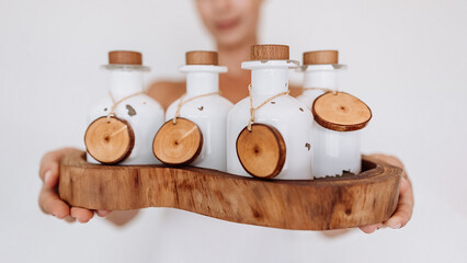 Hands holding different cosmetic bottles isolated on white background. SPA natural organic cosmetics with essential oils, packaging design with wooden parts. Advertising, banner