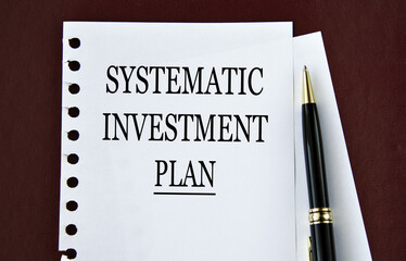 SYSTEMATIC INVESTMENT PLAN - words on a white sheet on a brown background with a pen