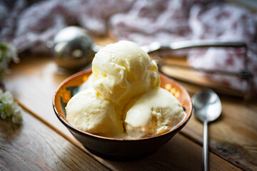 Homemade creamy ice cream in a small plate on a wooden background. Delicious dessert. Ice cream for dessert. Close-up. Vanilla ice cream.