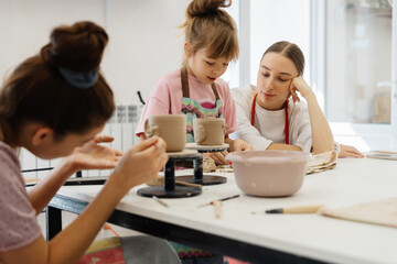 A mother and daughter enjoy pottery making together in a sunny studio