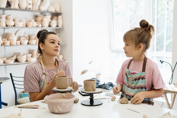 A mother and daughter enjoy pottery making in a bright studio space