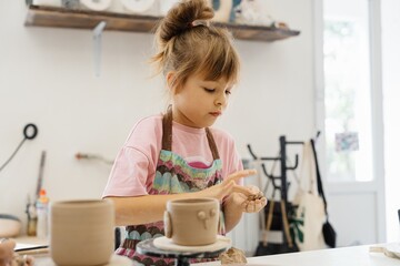 child practicing pottery in a creative studio during the day