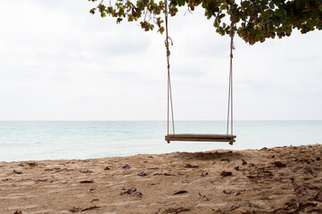A wooden swing on the tropical island beach