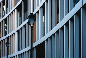 vintage street lamp stands elegantly in front of modern building with curved architecture during late afternoon light, showcasing contrast between traditional and contemporary design elements