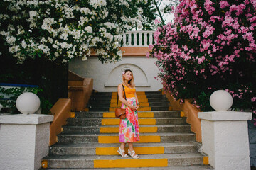 Pregnant girl in the park against the background of blooming oleander trees
