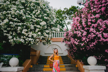 Pregnant girl in the park against the background of blooming oleander trees