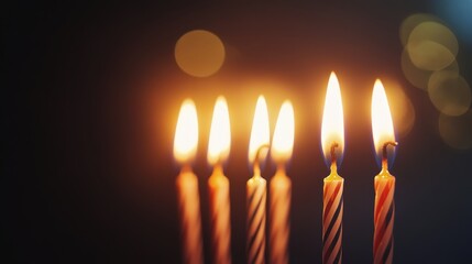 Fototapeta premium Five lit birthday candles on dark background.