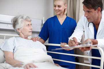 Medical, team and elderly patient in hospital bed for healthcare results, surgery checkup and progress notes. Senior woman, nurse and doctor with clipboard in clinic for health support and recovery