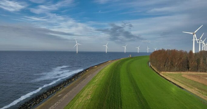 flying over a water barrier, dijk, along the water line, wind turbines, clean energy, The Netherlands, flood protection. typical dutch scene.