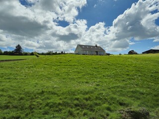 Cumulus Clouds Over a Grassland with Trees and a House © Studio-M