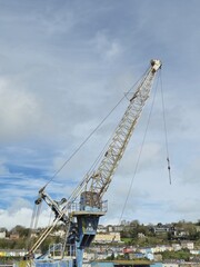 Fototapeta premium Construction Crane Near Water with Vehicles and Cloudy Sky