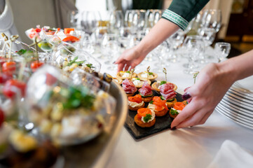 beautifully arranged buffet featuring variety of gourmet appetizers on table. Delicate finger foods are artistically presented, alongside elegant glassware, creating an inviting atmosphere for dining.