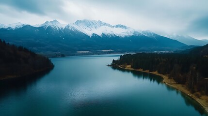 Naklejka premium Serene mountain lake with snow-capped peaks reflecting in the tranquil water.