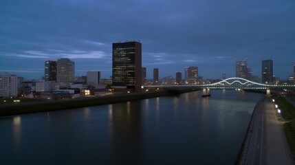 A nighttime cityscape featuring buildings, a river, and a bridge illuminated by city lights.