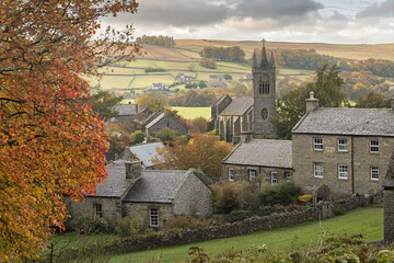Naklejka premium Charming village landscape with autumn foliage and historic church
