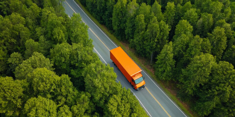 Aerial view of a orange transportation truck on an empty road in middle of a green trees forest