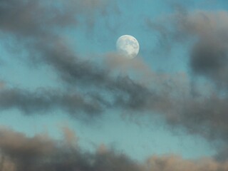 Bright moon among the clouds with blue sky in the background. 