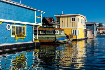 A row of colorful houses sit on the water, with a blue house in the middle