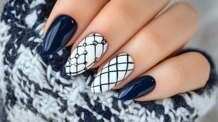 Elegant blue and white nail art design featuring geometric patterns on a young woman's hand against a cozy knit background
