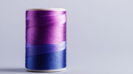 Colorful thread spool with purple and blue gradients isolated on light background for sewing and crafting projects.