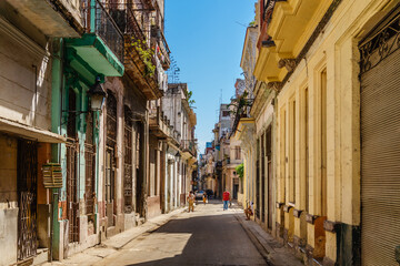 A narrow street with a few buildings and a person walking down it