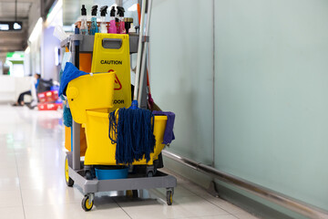 A yellow cleaning cart with a yellow bucket and a yellow mop
