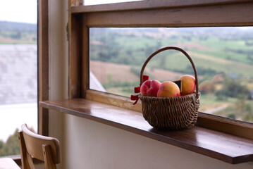 Apples in a basket placed on a wooden counter in the living room, looking out over a mountain view.