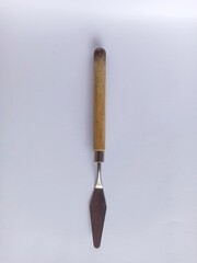 Art palette knives lie on a white art canvas. ainless painting palette knife with wooden handle. Palette knives, isolated on white. set new painting palette knives.