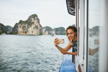 Woman, selfie and smile on tourist boat with journey, water and memory on vacation at tropical...
