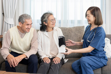Obraz premium senior couple sitting on couch listening to visiting nurse giving advice,physical examination and checking blood pressure at home,elderly health care,home health care,personal care services