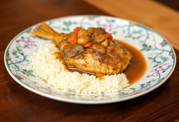 A medium shot of a plate with a chunk of fish stewed in gravy
