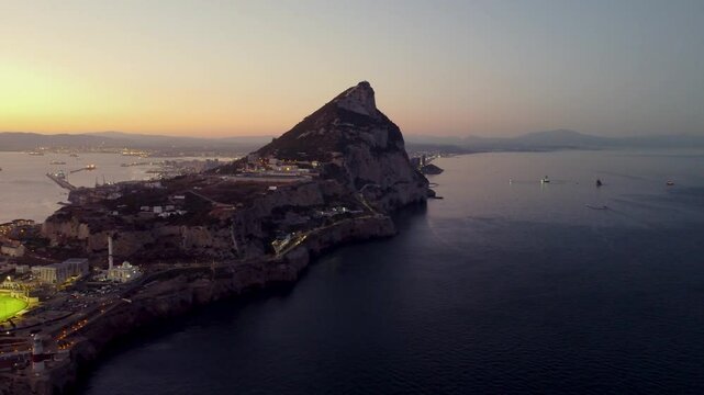 Aerial view of Gibraltar at sunset. Street lights on. Europa Sports Complex Stadium with night light on. Travel destination. Bay of Gibraltar. City of Gibraltar and La Linea, in background. Track left