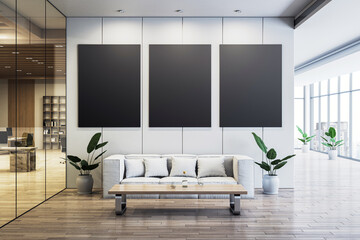 Modern office waiting area with three blank vertical black canvases on a wall, white sofa, wooden...