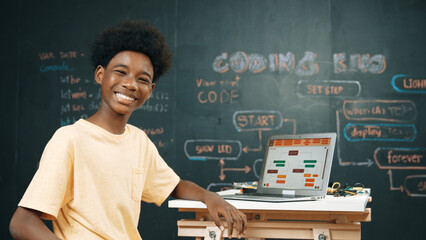 African boy using laptop programing system or coding prompt and turn around to smile to camera....
