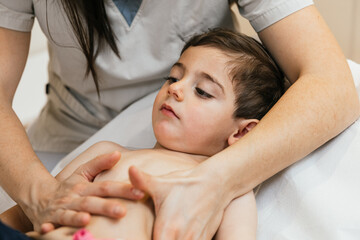 Physiotherapist performing respiratory physiotherapy on child's chest