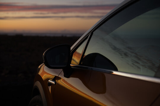 Reflejo del atardecer en la ventanilla y carrocer&iacute;a de un coche (formato horizontal)