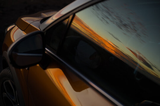 Reflejo del atardecer en la ventanilla y carrocer&iacute;a de un coche (formato horizontal, vista cenital)