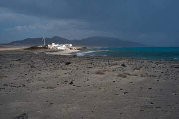 Pueblo de casas blancas junto al mar con la tormenta aproximándose, en El Cofete (Fuerteventura,...
