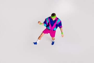 Fototapeta premium Young man in vibrant retro sportswear performing dynamic exercise on a bright white background, emphasizing healthy lifestyle