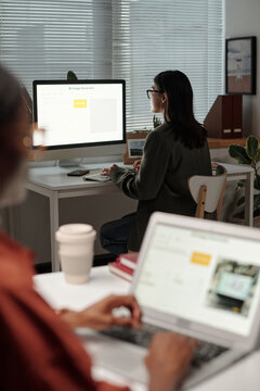 Focus on young female designer looking at desktop computer screen with AI image generator in working environment