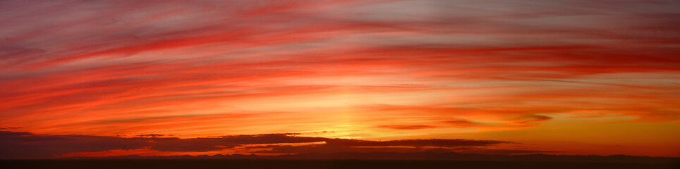 Fototapeta premium Wide panorama of a glowing orange striped sunset sky