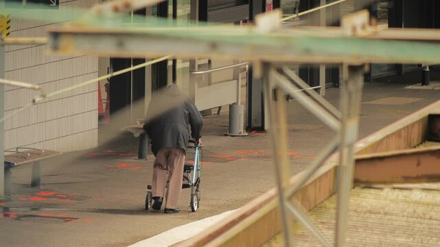 An unknown senior man uses his mobility walker or rollator on the railway platform