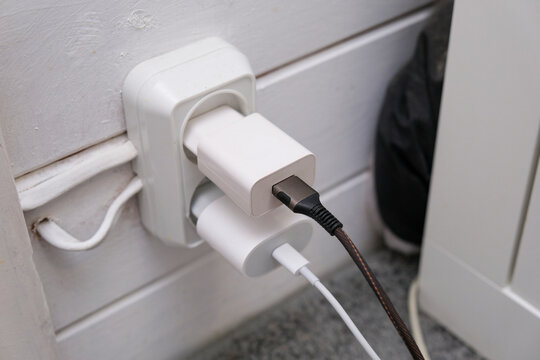 Overloaded outlet with an extension and many sockets plugged in, risk of fire and short circuit in a wooden house.