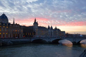 Fototapeta premium Paris city historic center with Pont au Change bridge across Seine river, Conciergerie palace Gothic revival architecture style at sunset twilight, Paris evening view, France