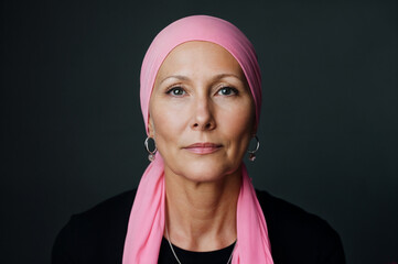Empowered middle-aged woman wearing a pink headscarf, symbolizing strength and resilience in the fight against breast cancer