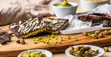 Homemade Dubai chocolate with white and dark chocolate, pistachio cream, kadayif and pistachios on wooden background