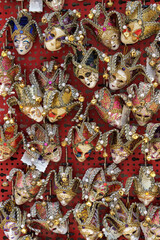 Traditional Venetian masks in a shop window on red background