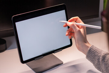 Close-up, female using her tablet while siting in the office. Tablet white screen mockup