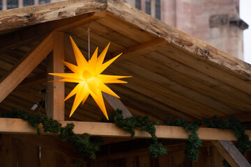 Bright Yellow Star Decor on Rustic Wooden Structure in Christmas Market. High quality photo