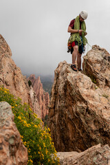 Rock climber on the top of mountain pulling up rope after climbing